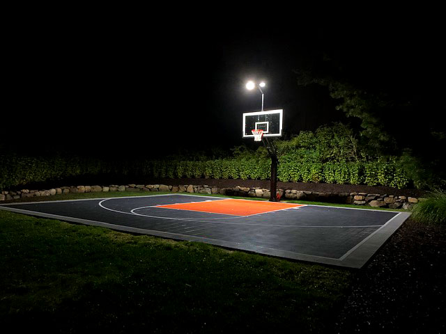 Backyard basketball court at night with lighting