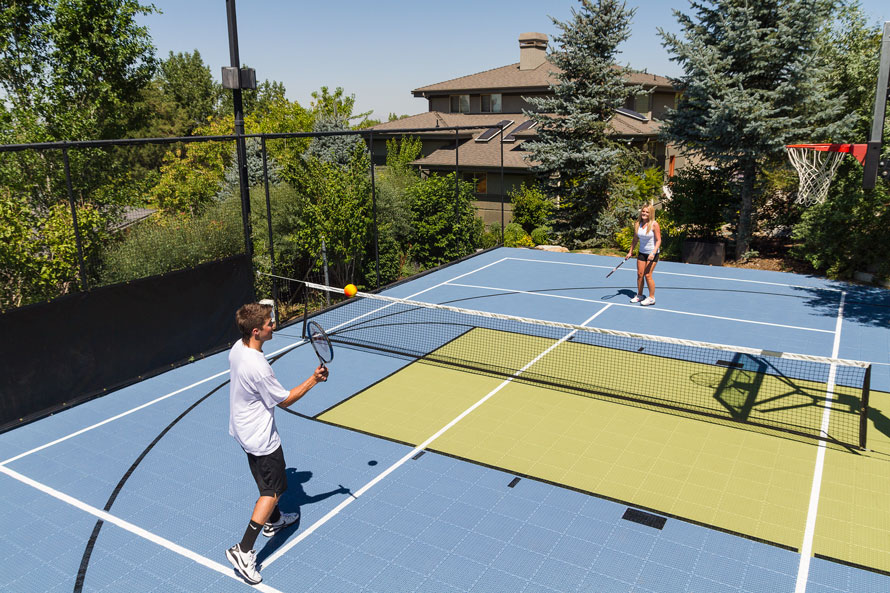 Two teens playing tennis on a backyard court