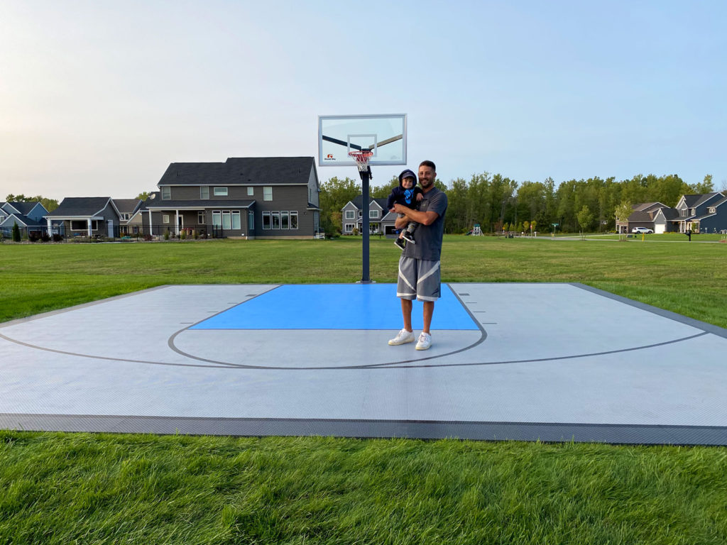 Father holding his son and standing on a backyard basketball half court