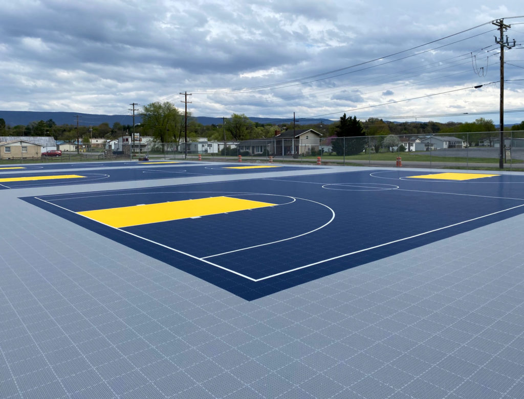 Full basketball courts with Outdoor Revolution in gray, dark blue, and yellow