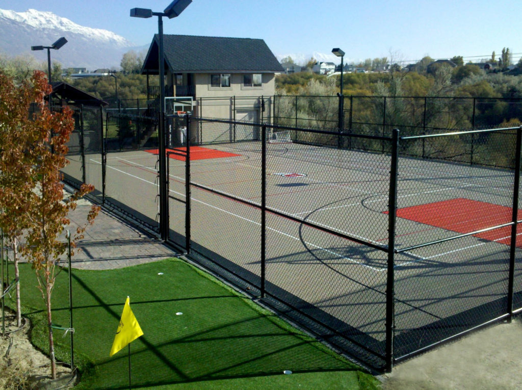 Large outdoor graphite and red multi-court with fencing and ball containment netting all around