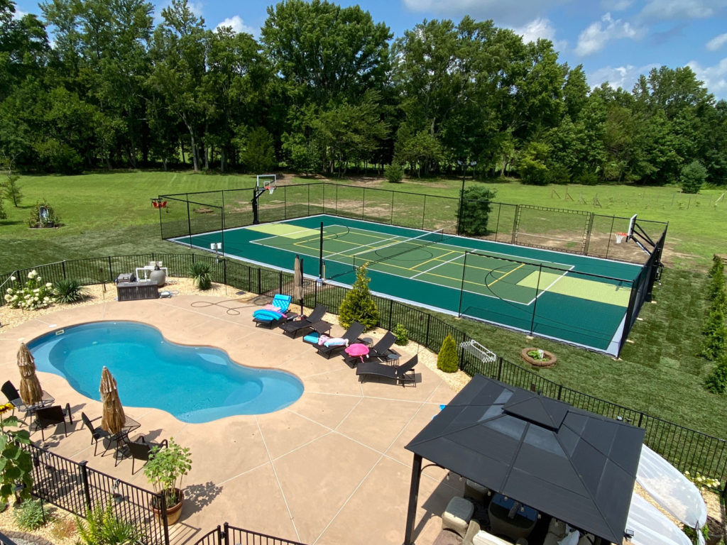 Full size green outdoor multi-court next to a swimming pool