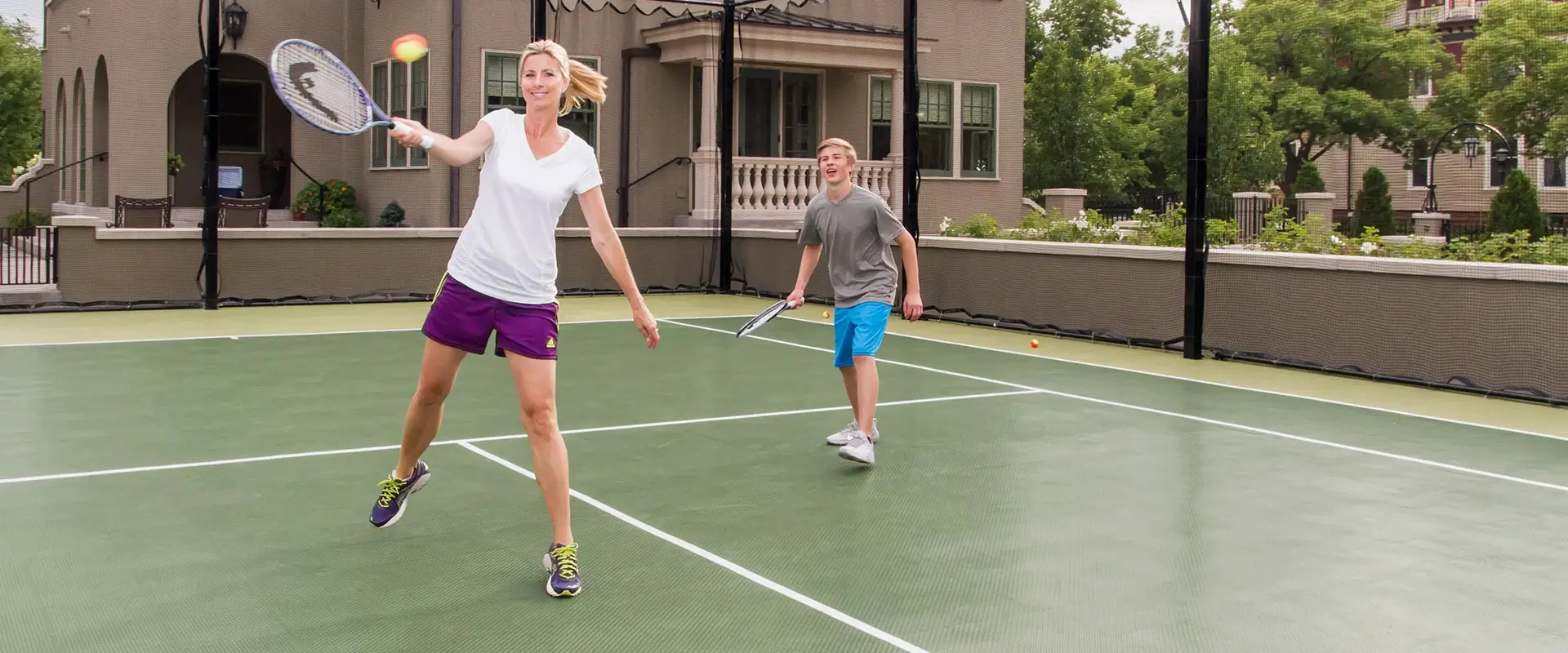 Mother and son play tennis in their backyard