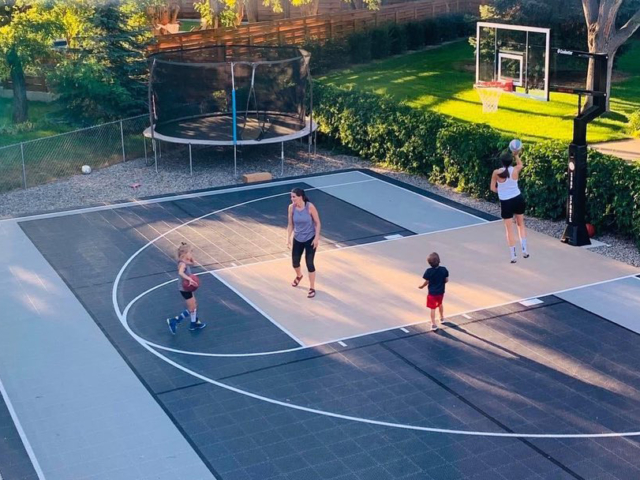 Family playing basketball on a backyard multi-court