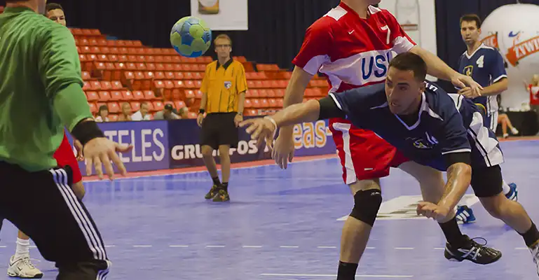 commercial handball A handballer dives and throws for a goal during a handball match on a SnapSports surface.