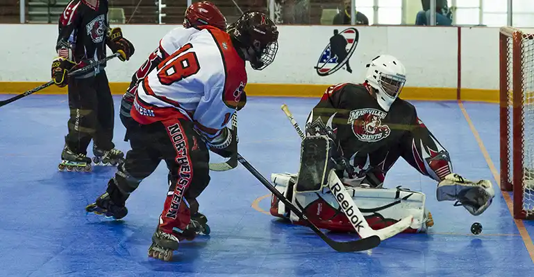 commercial hockey A hockey goalie stops a puck during a college inline hockey match on SnapSports flooring