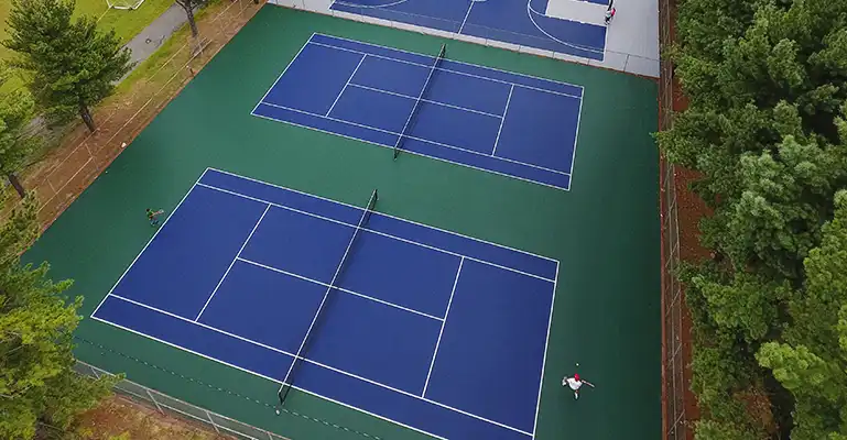 commercial tennis courts Two people play tennis in a public park on a court resurfaced with DuraCourt.