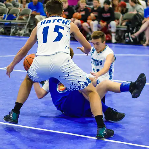 safety player comfort Two basketball players fall on the court during an intense game.