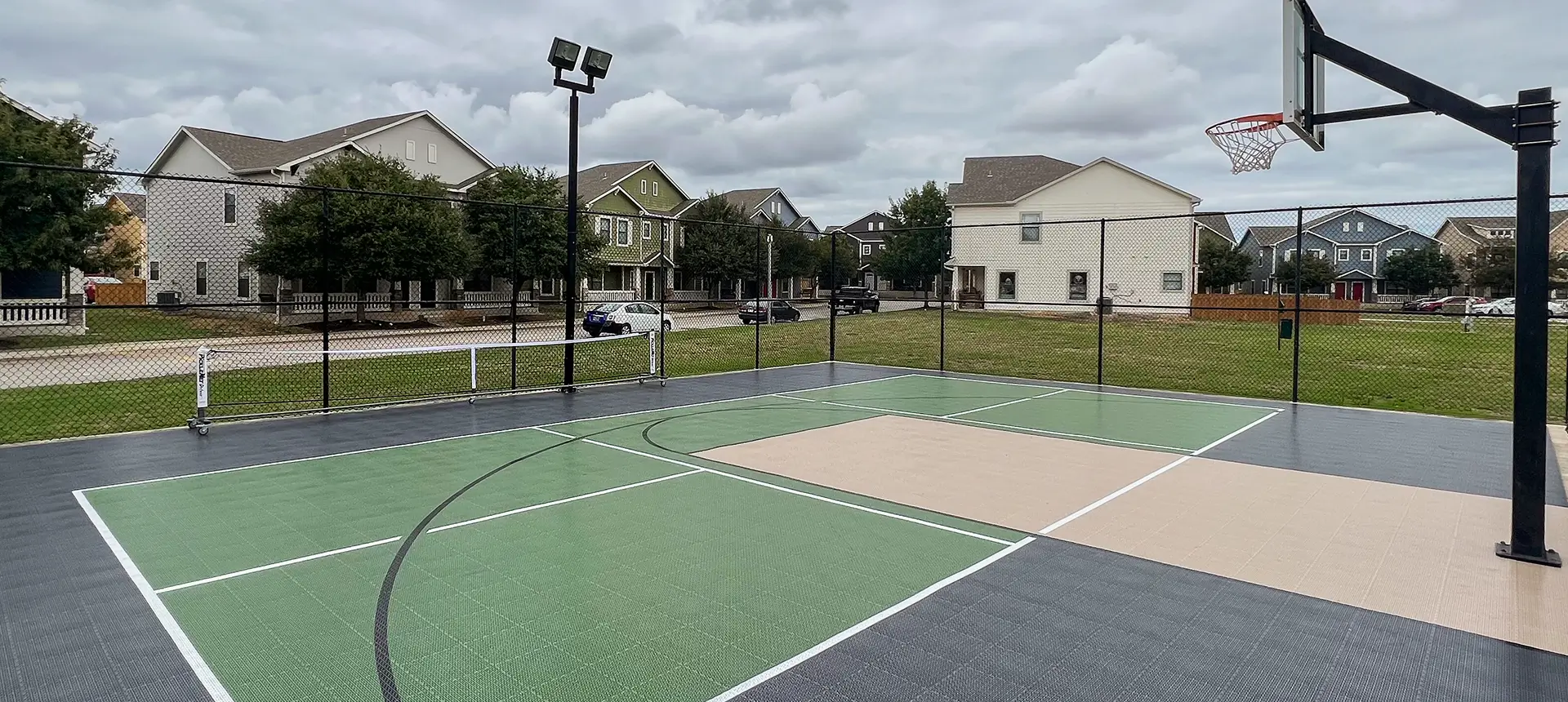 A home court in a family's back yard with pickleball and basketball lines.